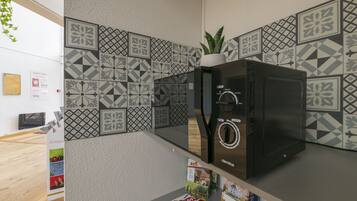 Une cuisine moderne avec des carreaux décoratifs, un réfrigérateur noir et une plante en pot.