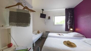 Habitación de hotel con dos camas, televisor, ventana con cortinas y un escritorio pequeño con un libro y gafas.