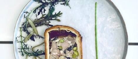 Un plato con un guiso de carne, vegetales verdes y salsa verde.