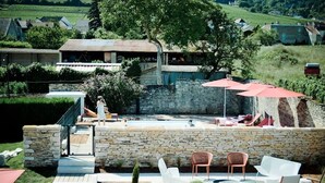 Un patio al aire libre con paredes de piedra, piscina y mobiliario exterior.
