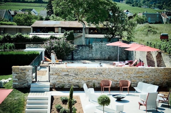 Un patio al aire libre con paredes de piedra, piscina y mobiliario exterior.
