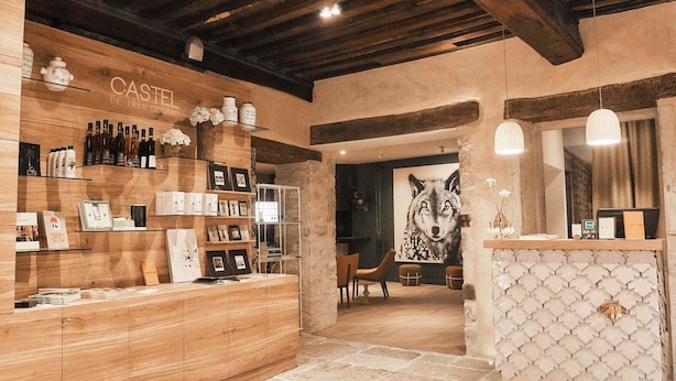 Un interior rústico con estantes de madera exhibiendo diversos objetos, un mostrador de recepción y una gran obra de arte enmarcada con un lobo.