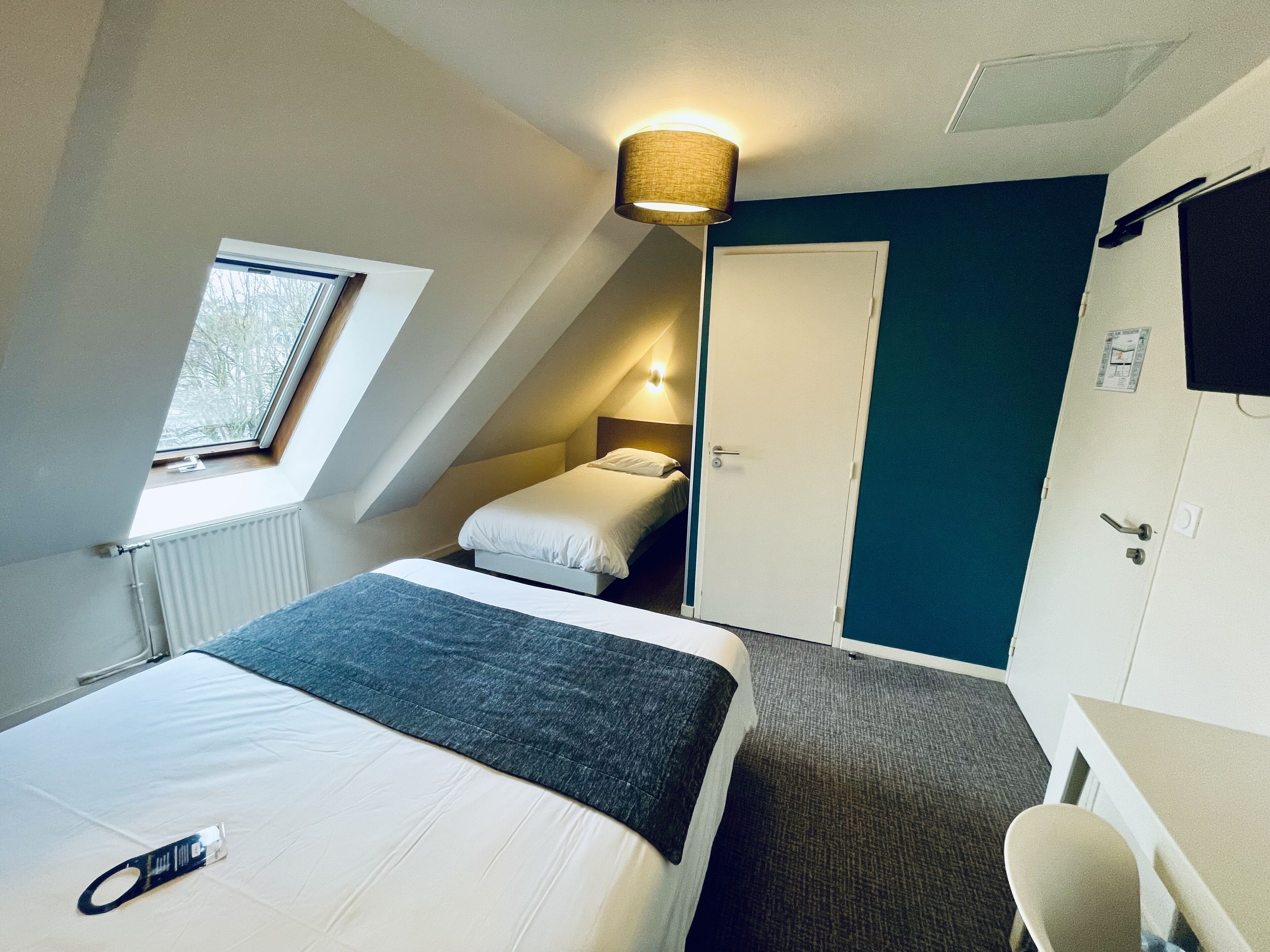 Une chambre à coucher avec un lit, un bureau, une chaise, une fenêtre et une porte.