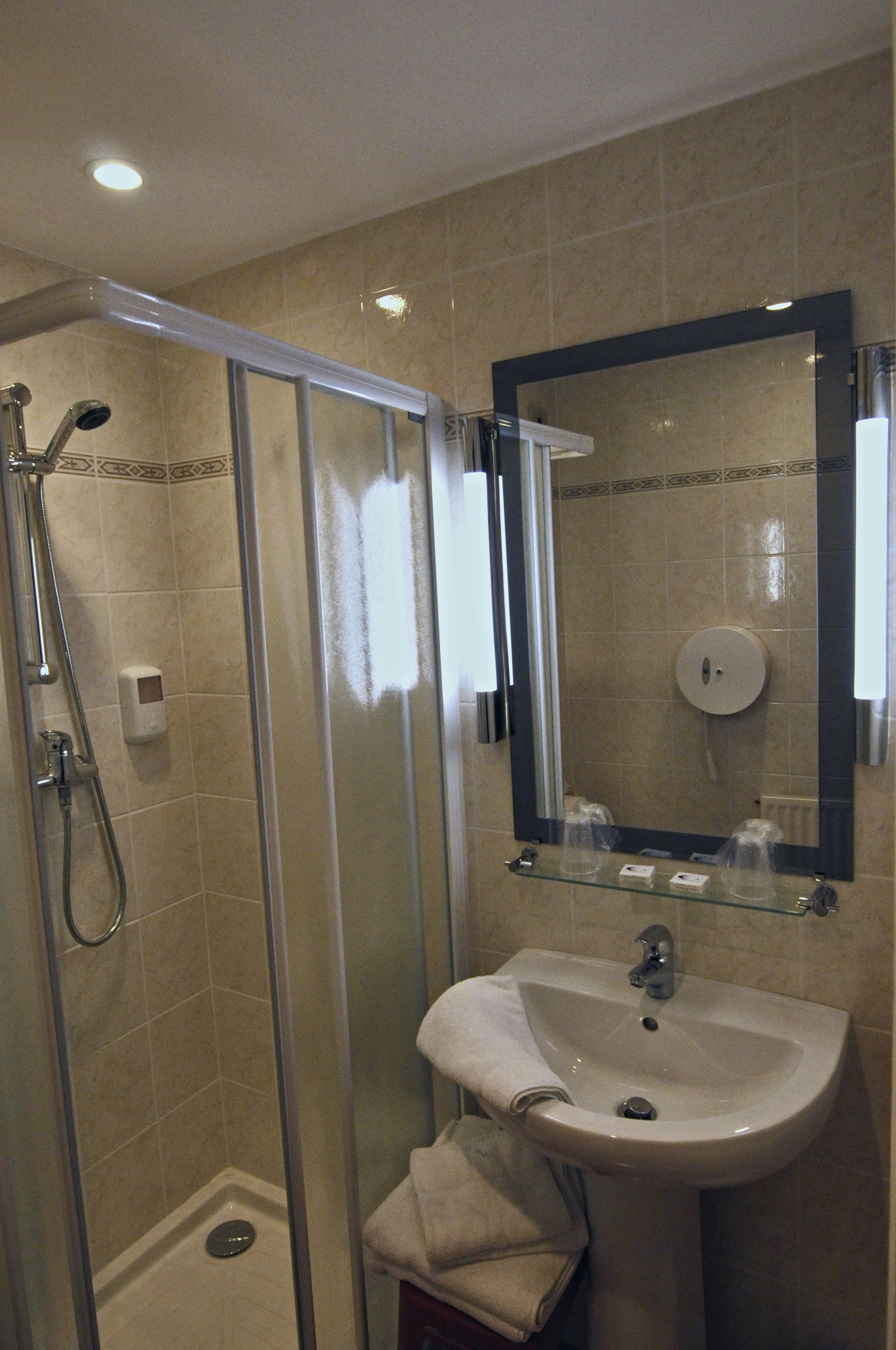 A bathroom with a glass-enclosed shower, a sink with a mirror above it, and a toilet.