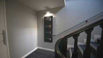 Una escalera con barandilla y un cartel en la pared que indica los pisos.
