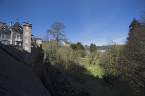 Surrounded by a serene garden, this historic building features a traditional stone tower and steeply pitched roof.