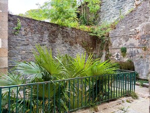 A stone wall with greenery and a metal fence. - Hôtel Du Port (Morlaix)