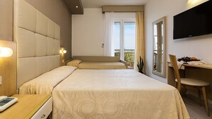 A hotel room with a large bed, a desk with a chair, a TV mounted on the wall, and a window with curtains. - Hotel Torino (Jesolo)