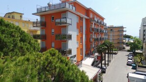 A multi-story building with balconies, a parking area, and a clear sky. - Hotel Torino (Jesolo)