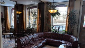 A spacious living area with a large leather sectional sofa, a coffee table, and a dining area with chairs and a table. - Hôtel Régina (La Bourboule)