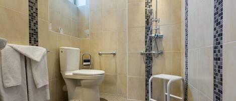 Un baño con inodoro, ducha y un taburete pequeño.