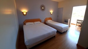 Habitación de hotel con dos camas, suelo de madera e iluminación en la pared.
