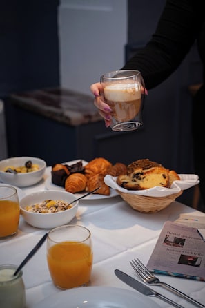 A breakfast table with croissants, muffins, and orange juice.