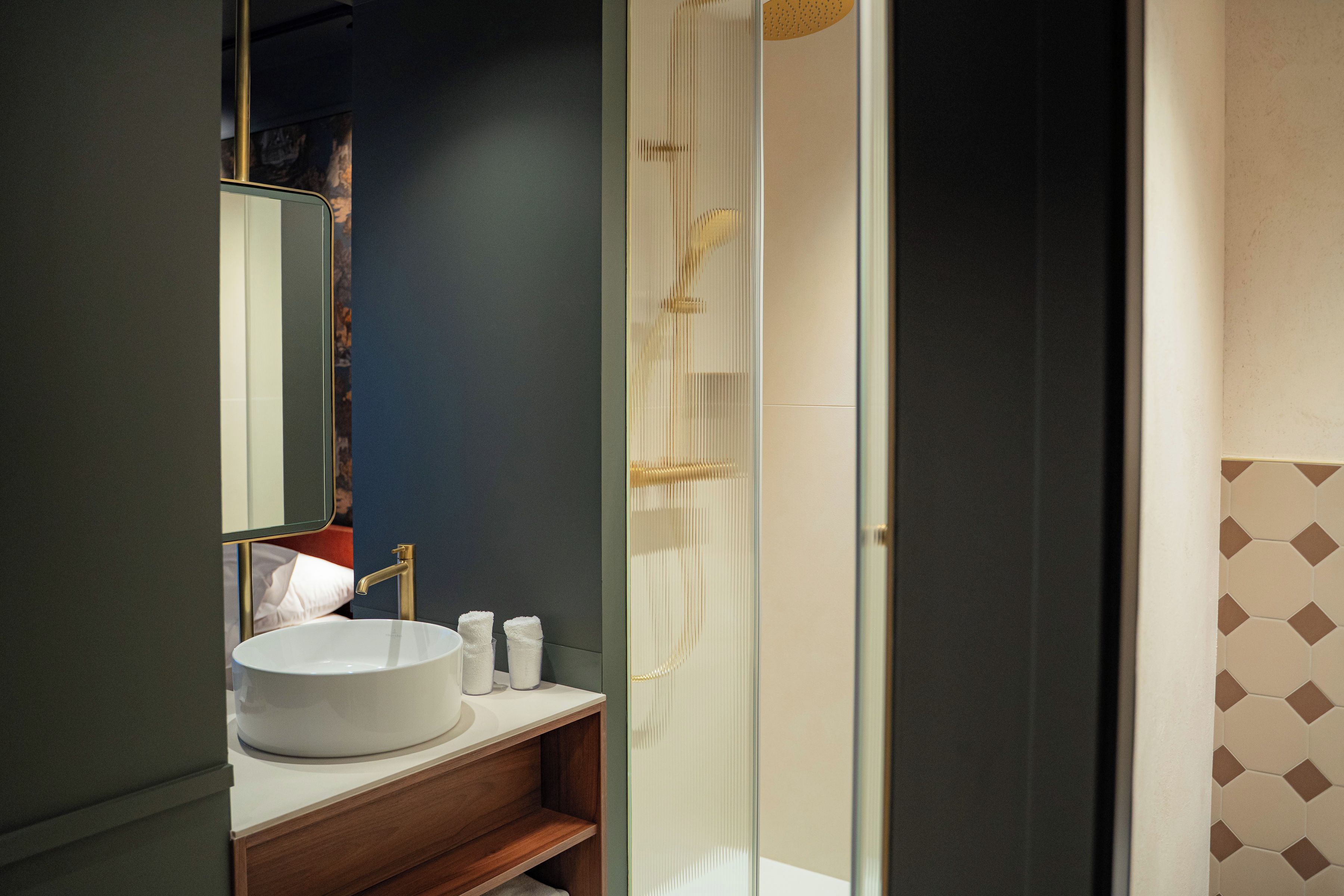 Une salle de bain avec un lavabo blanc, un miroir et une douche.