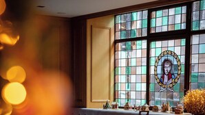 A dining area with a table set for two, a bench, and a window with stained glass. - Hôtel Le Rapp (Colmar)