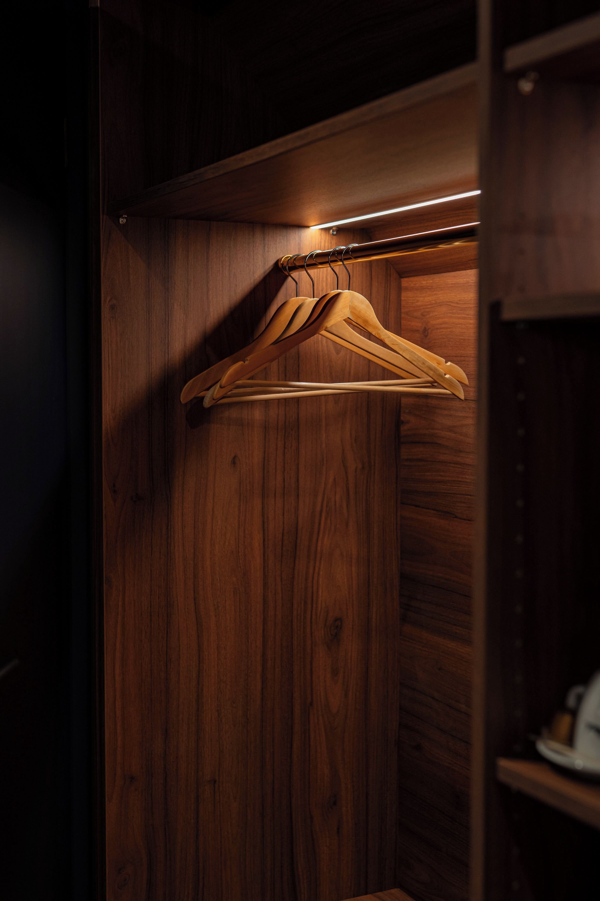 A wooden closet with a hanging rod and a shelf.