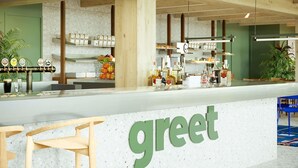 Un mostrador con un letrero que dice 'greet', estantes con bebidas y una zona de estar.