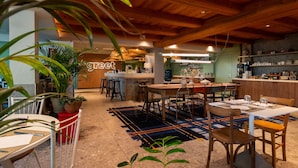 A restaurant with wooden ceiling beams, a bar area, and a seating arrangement with tables and chairs. - greet Hôtel Colmar (Colmar)