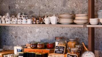 A kitchen counter with various kitchenware, including mugs, teapots, and plates, and jars of spices and condiments.