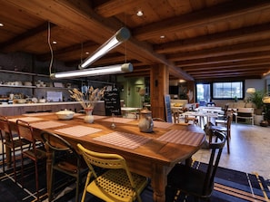 A restaurant with wooden tables and chairs, a chalkboard menu, and hanging pendant lights. - greet Hôtel Colmar (Colmar)