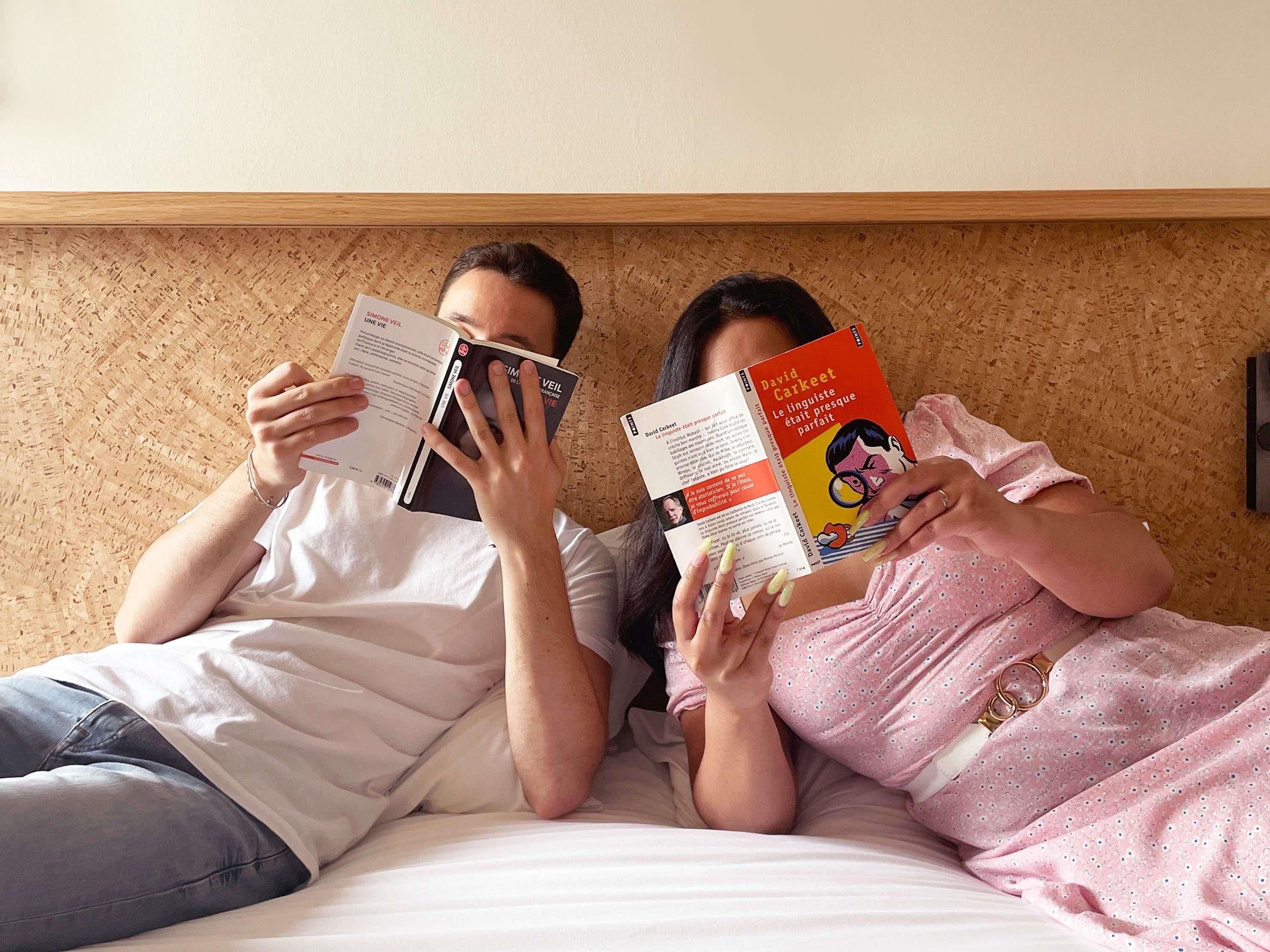 Deux personnes sont allongées sur un lit, en train de lire des livres.