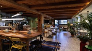 Un comedor amplio con una larga mesa de madera, varias sillas y un techo rústico.