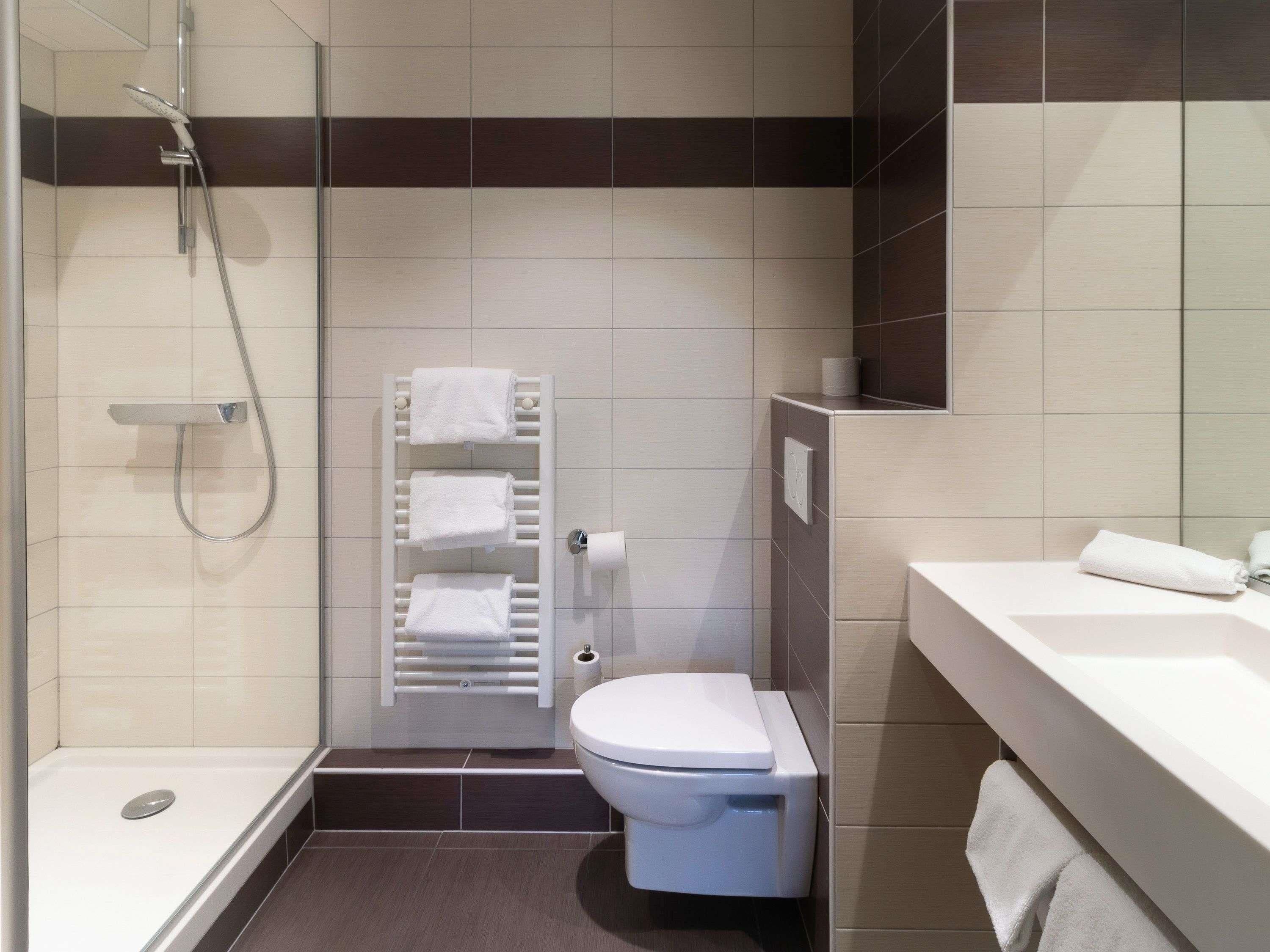 Een moderne badkamer met douche, toilet en wastafel.