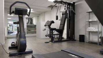 A gym with exercise equipment including a treadmill, elliptical, and weight machines.