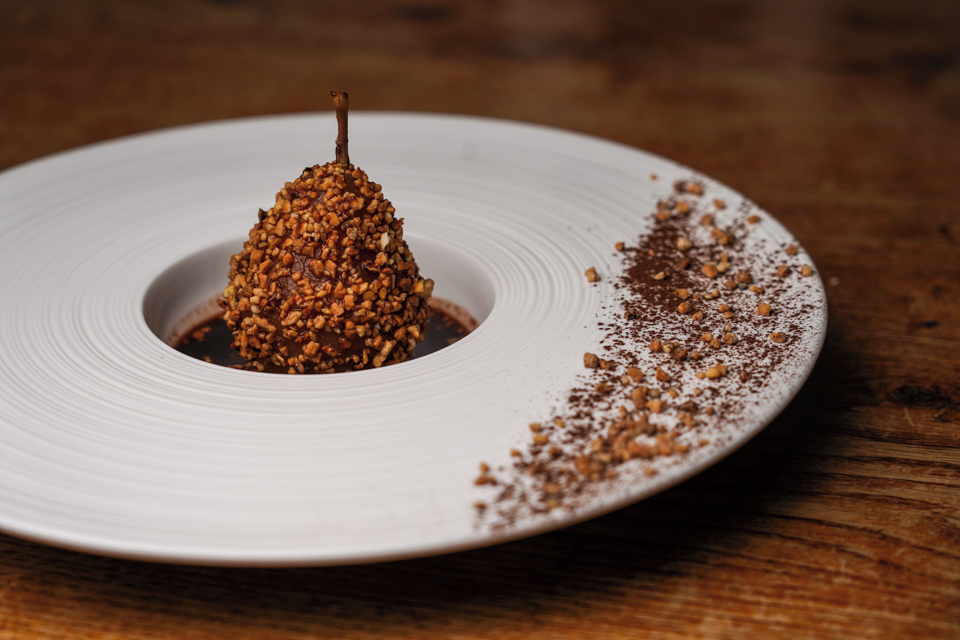 A white plate with a dessert on a wooden table.