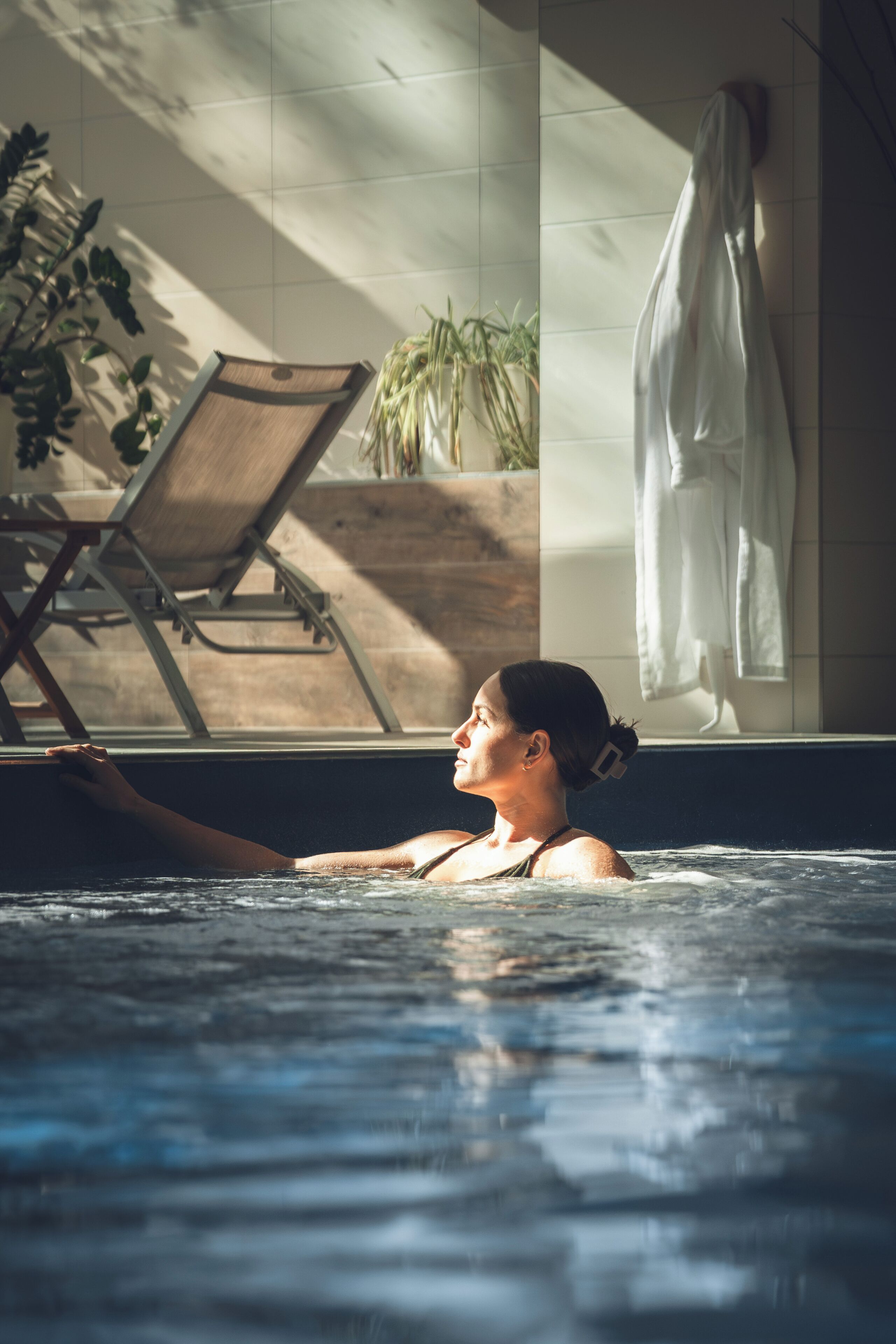 Une personne dans une piscine, avec une chaise et un porte-serviettes en arrière-plan.