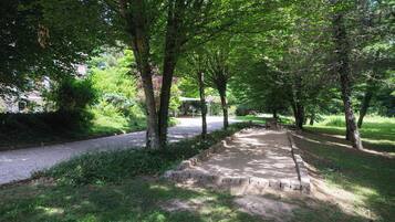 Un sendero bordeado de árboles en un parque, con bancos y una mesa de picnic.