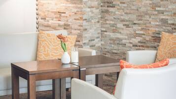 Una sala de estar moderna con una pared de piedra, un sofá blanco, una mesa de centro de madera y una lámpara.