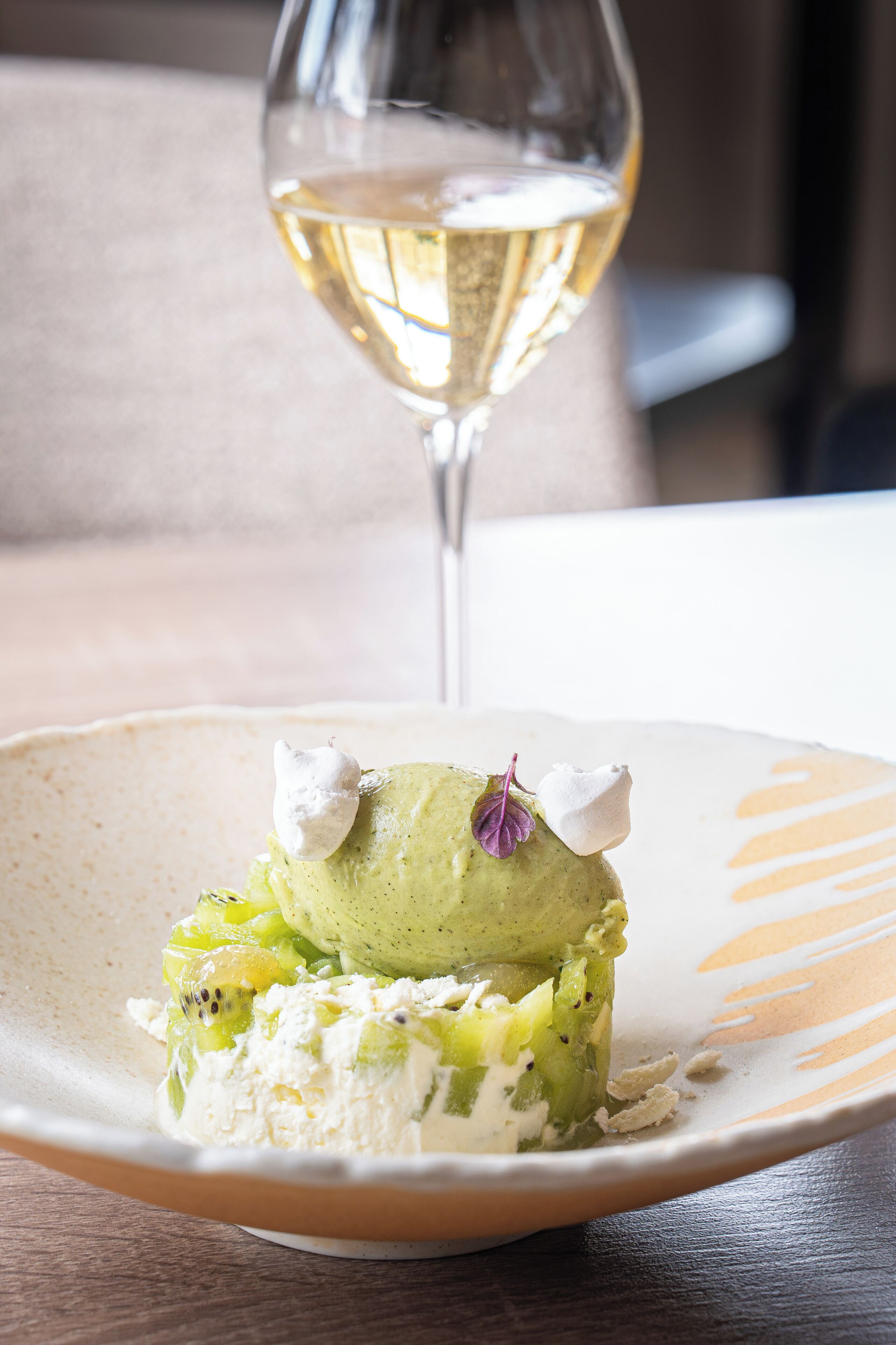 A dessert on a plate with a glass of white wine in the background.