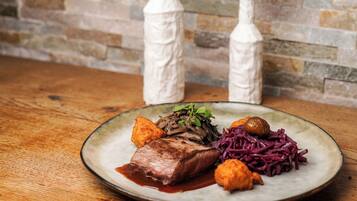 A plate of food with a steak, vegetables, and a sauce on a wooden table.