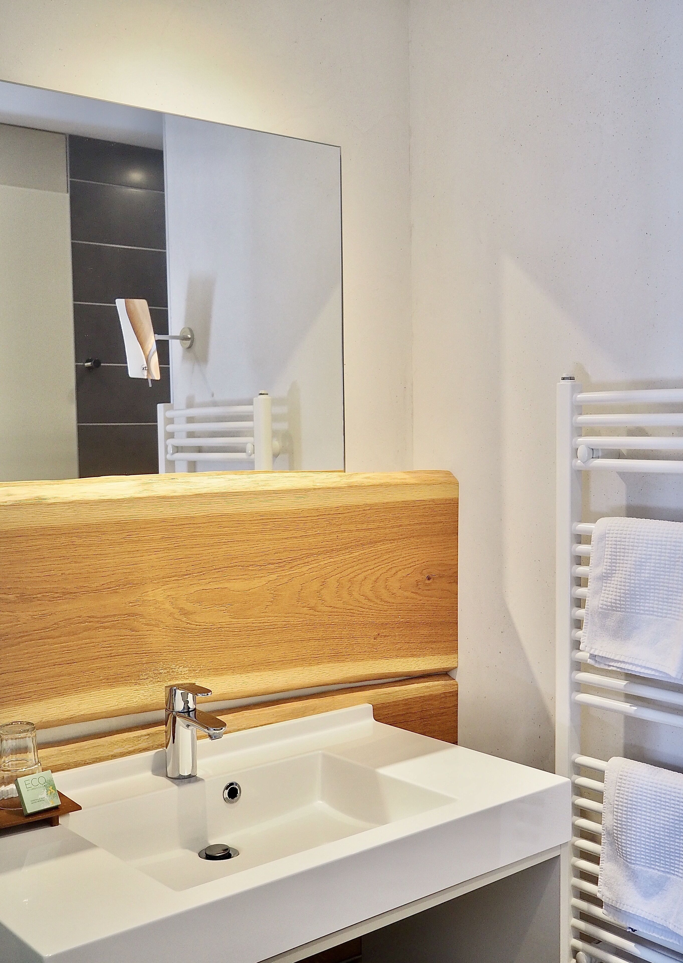 Une salle de bain moderne avec un lavabo blanc, un meuble-lavabo en bois et un porte-serviettes.