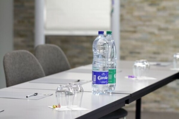 Una sala de reuniones con una mesa de conferencias, botellas de agua, vasos y una pizarra.