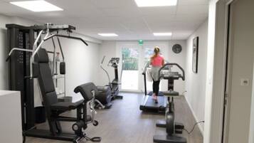 A gym with treadmills, weight machines, and a bench.