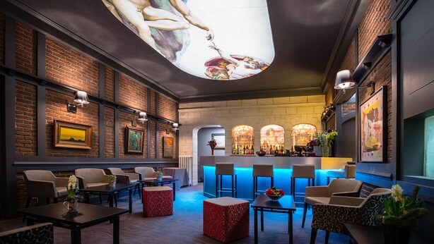 A modern lounge with a large mural, brick walls, and a bar area. - La Terrasse (Douai)