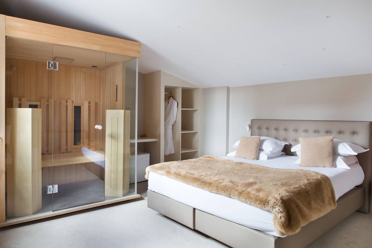 A modern bedroom with a large bed, a glass-enclosed walk-in closet, and built-in shelving.