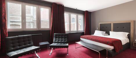 Habitación de hotel con cama, dos sillas, ventana y radiador.
