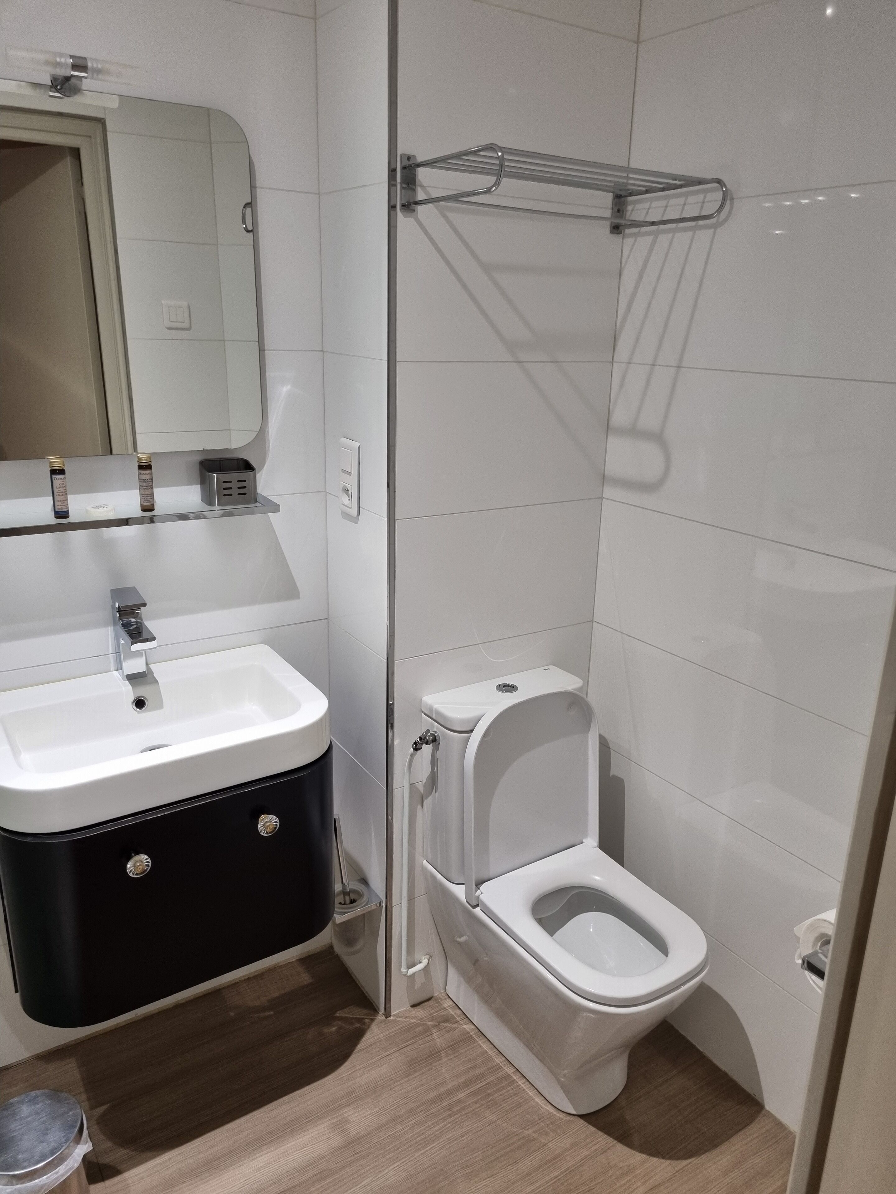 A modern bathroom with a white sink, black cabinet, and a toilet.