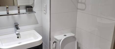 A modern bathroom with a white sink, black cabinet, and a toilet.