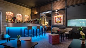 A bar area with a brick wall, bar stools, and a counter with various bottles. There are tables and chairs for seating, and a window with a view of the sea. - La Terrasse (Douai)
