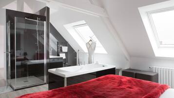 Une chambre moderne avec une douche en verre, une grande fenêtre et une couverture rouge sur le lit.