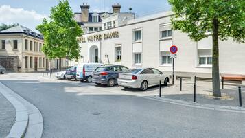Een straat met geparkeerde auto's, een gebouw met de tekst 'L'Hotel Notre Dame' en een parkeerverbod.