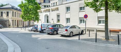 A street with parked cars, a building with 'L'Hotel Notre Dame' signage, and a no parking sign.