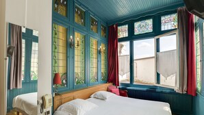 Una habitación con una cama grande, teléfono y ventana con cortinas.