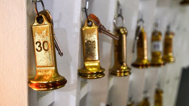 Una hilera de campanas doradas con los números 30, 31 y 32 colgadas en una pared.