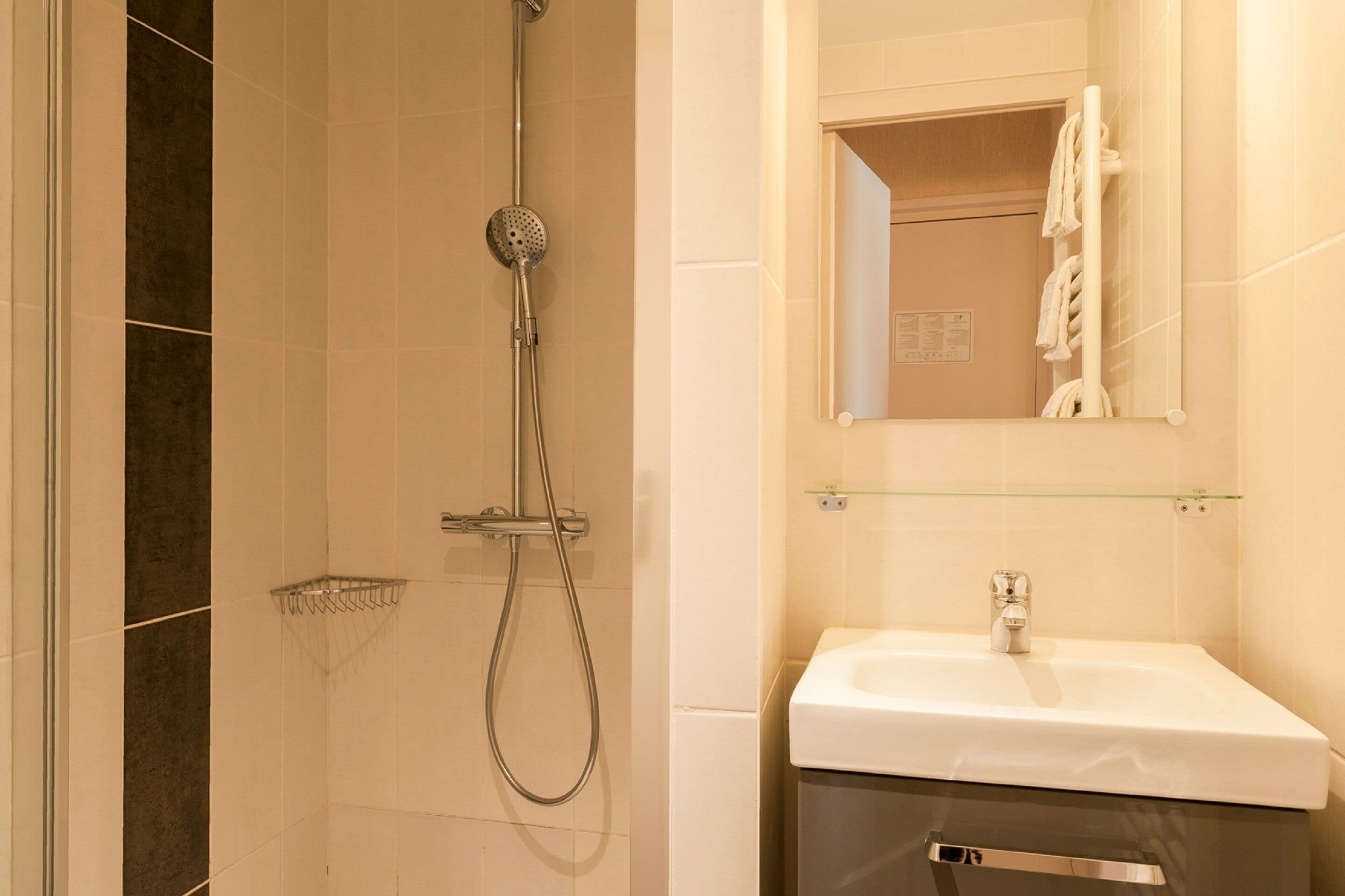 Un baño con ducha, lavabo y espejo.