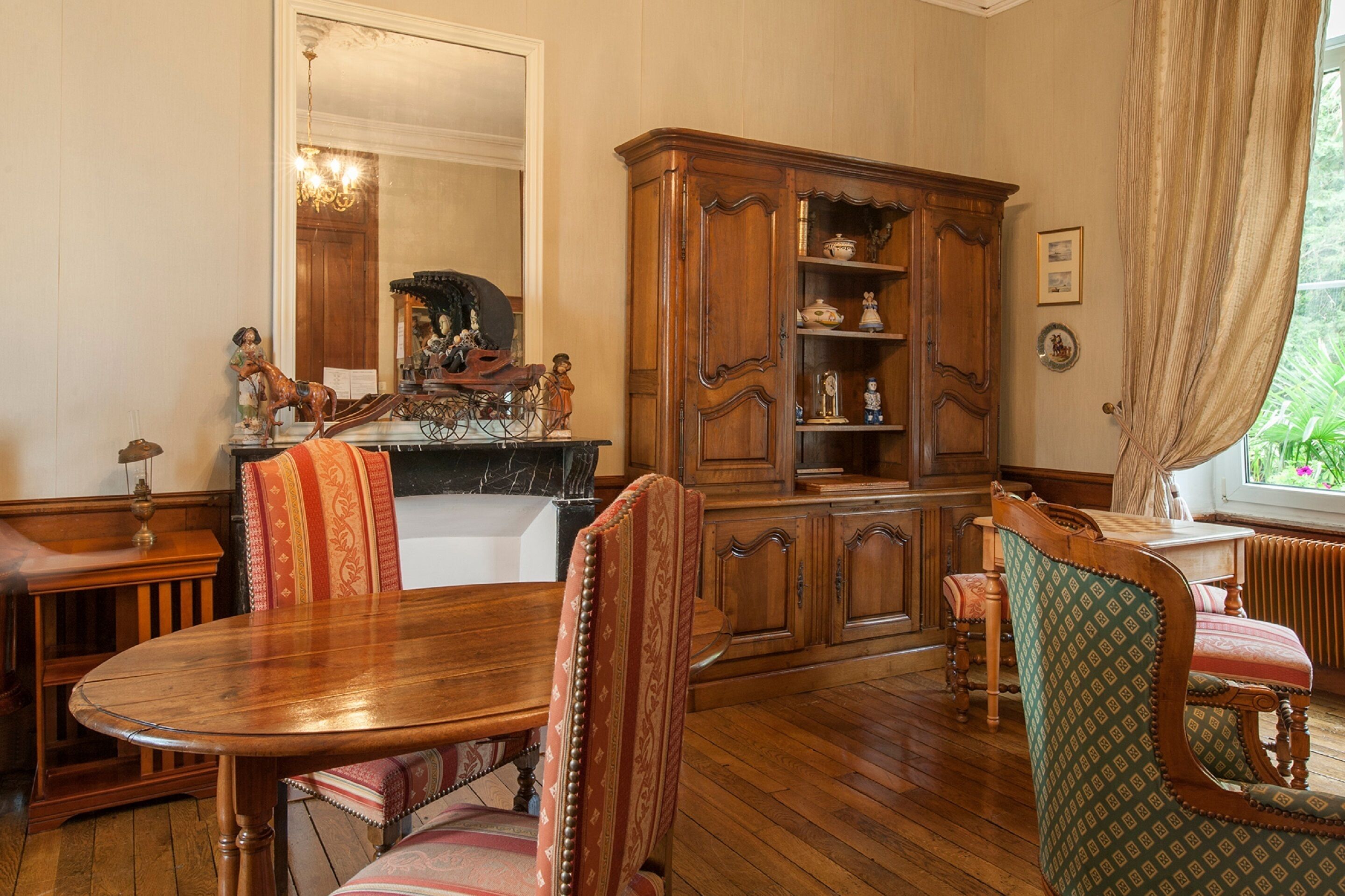A dining room with a wooden table, chairs, and a large wooden cabinet with shelves.